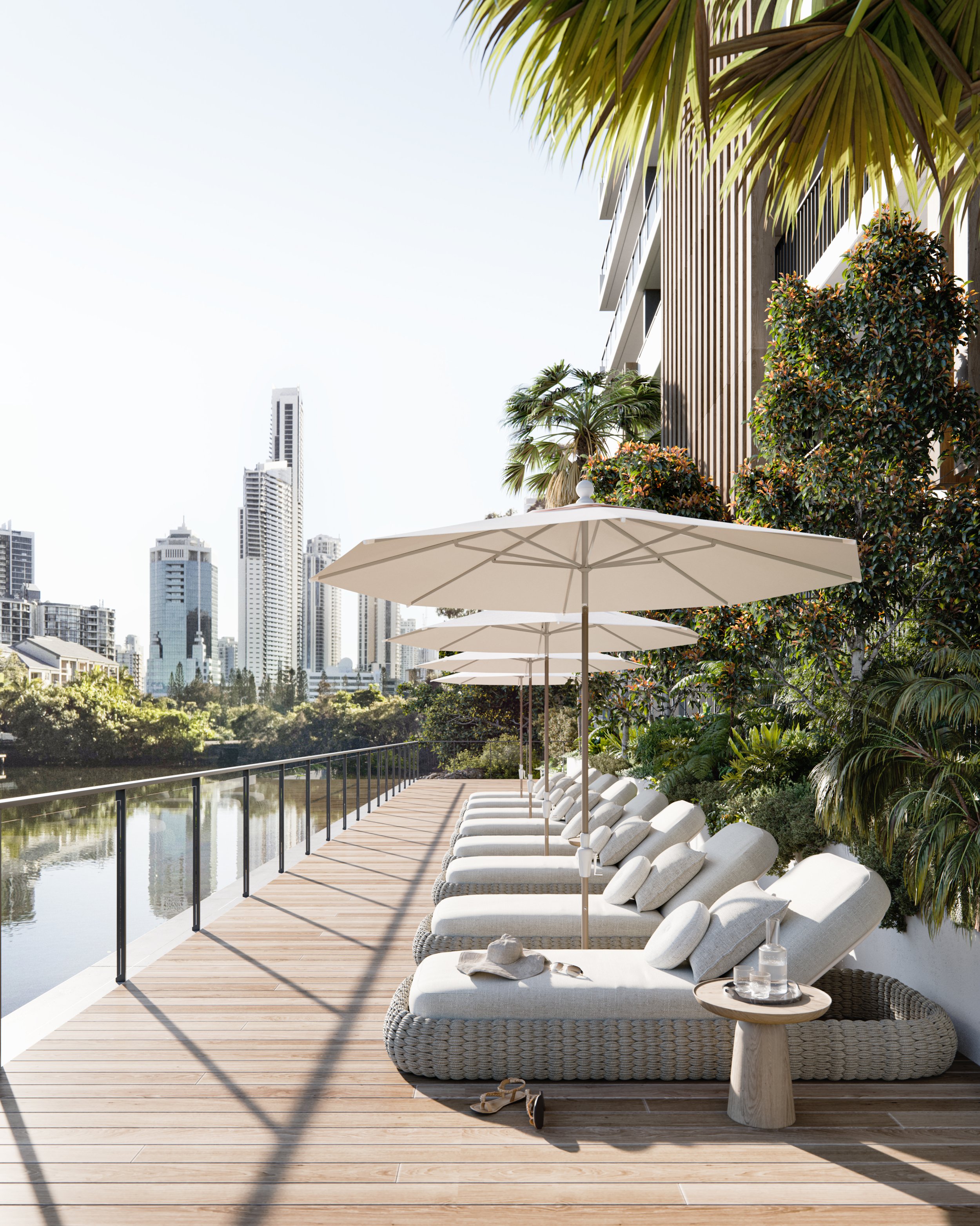 Poolside lounge chairs with umbrellas by a river, city skyline in background