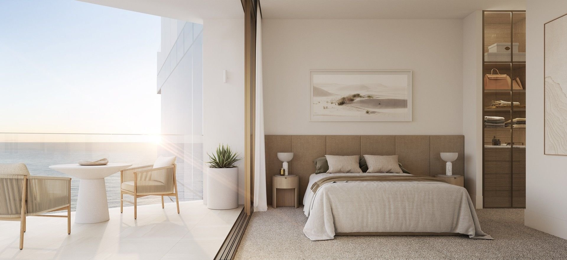 Modern bedroom with ocean view, featuring a comfortable bed, minimalist decor, two side tables with lamps, a framed landscape artwork, glass doors leading to a balcony with chairs and a table, and a wardrobe with glass doors.