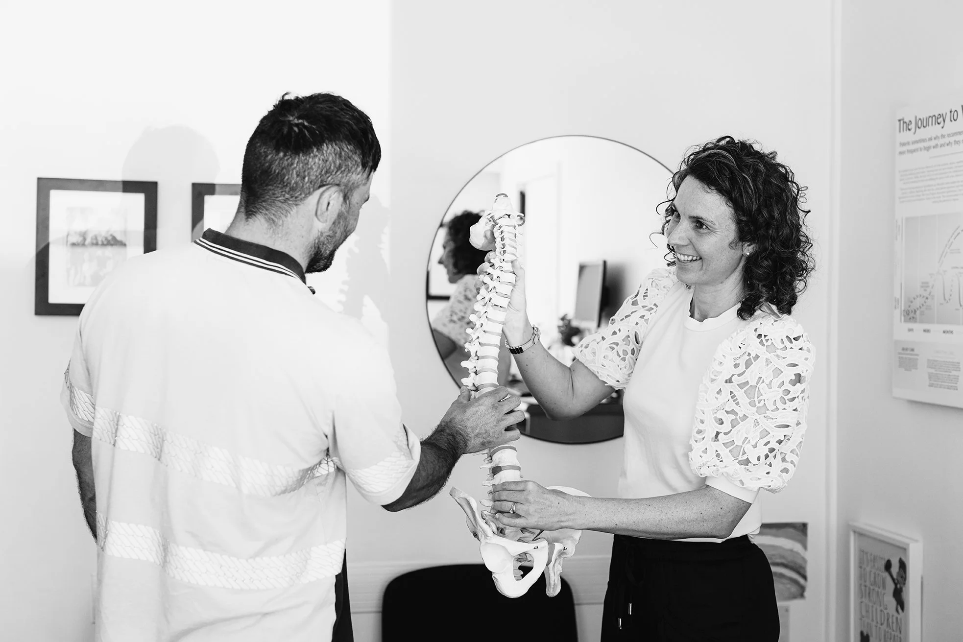 A chiropractor in Hastings explains the spine using a model to a patient.