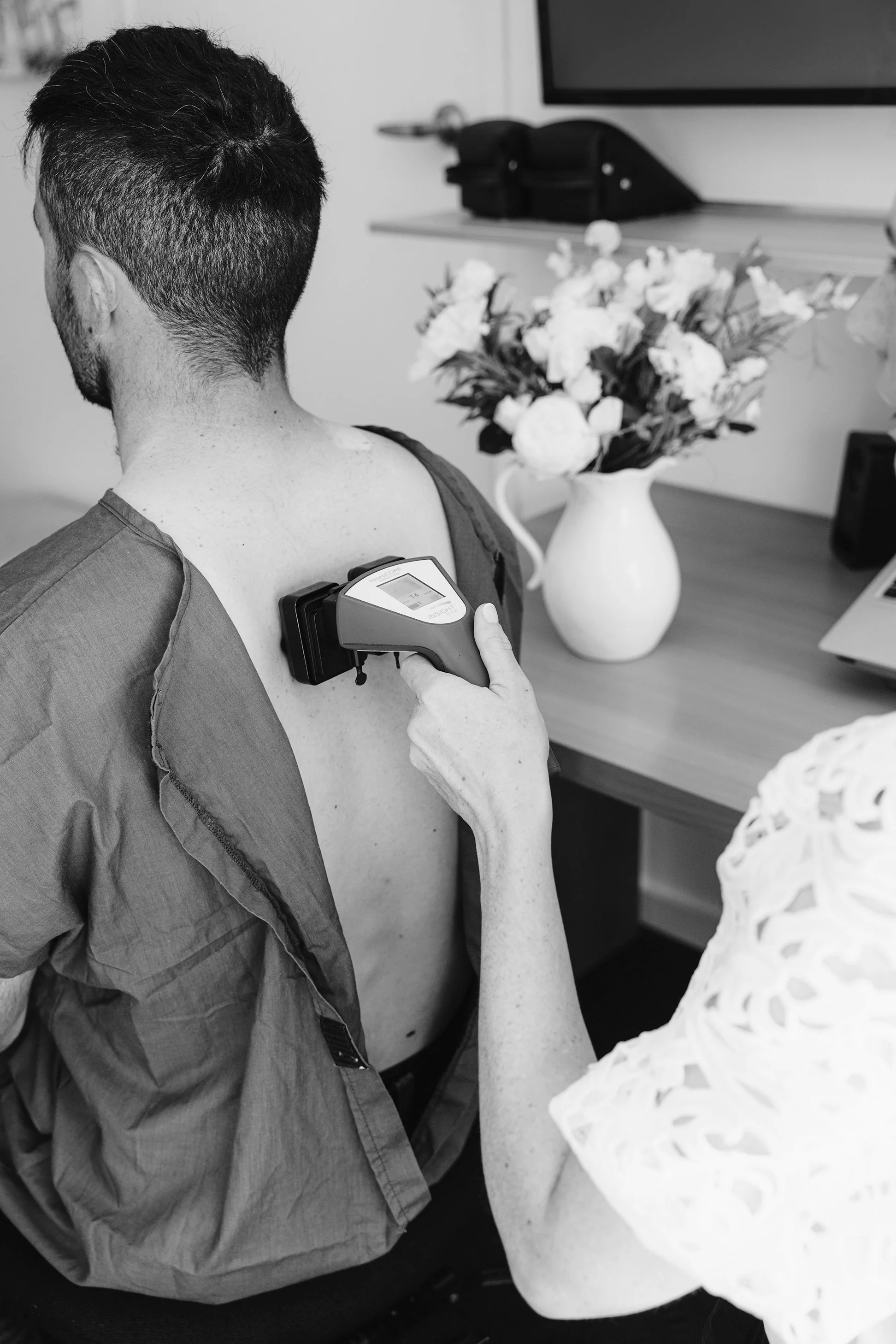 A chiropractor in Hastings uses a device to assess a patient's back, representing modern diagnostic tools.