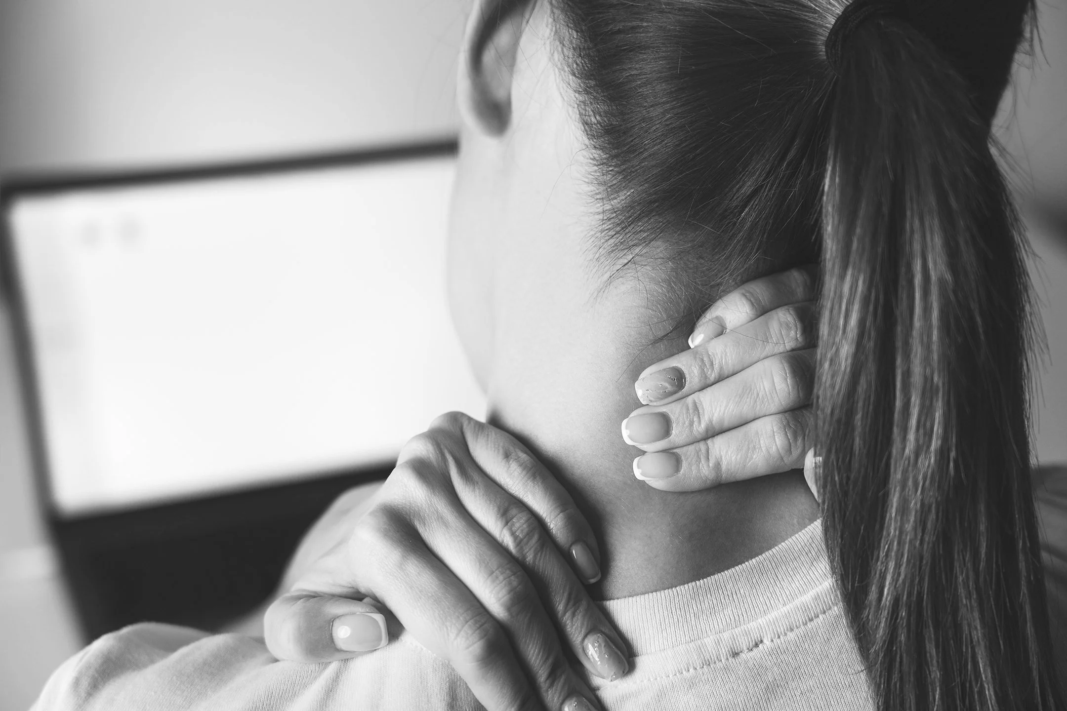 Black-and-white photo of a woman with neck pain, a symptom that can be treated with chiropractic care in Hawke's Bay.