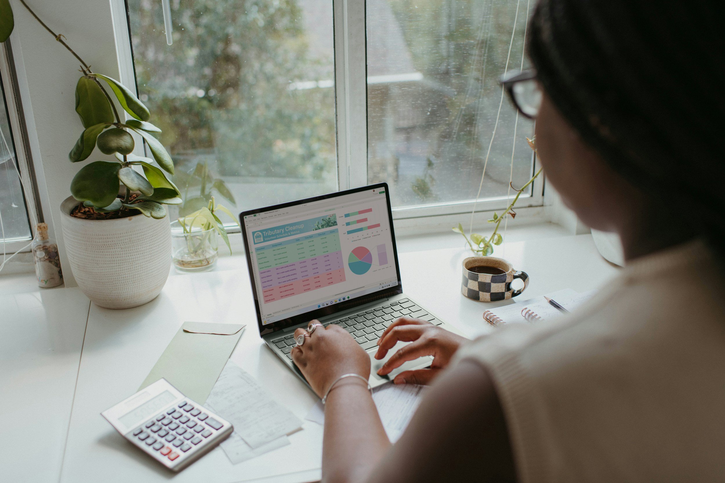 Woman typing on her computer that has charts and graphs on the screen.