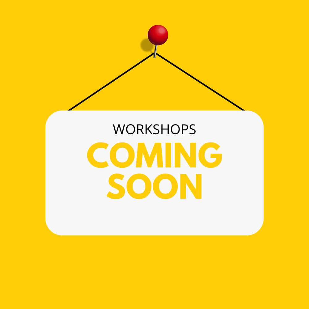 Sign with white background hanging on yellow wall, displaying the words 'Workshops Coming Soon' in black and yellow text.
