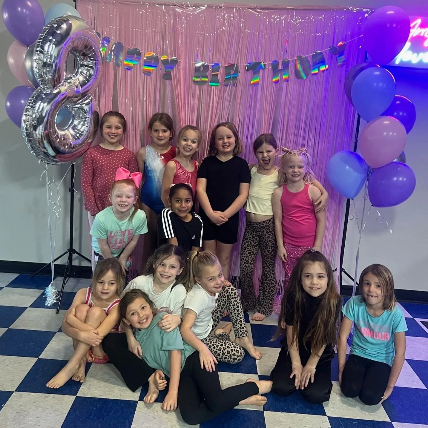People participating in a dance fitness class in a dark room with neon lighting.