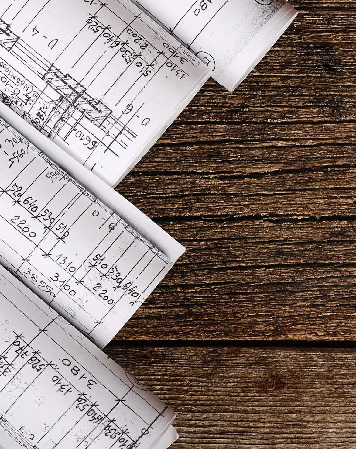 Close-up of rolled architectural blueprints on a wooden surface.