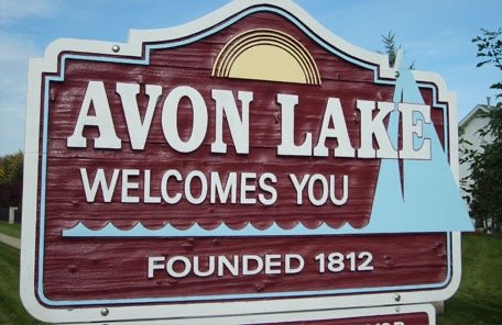 Sign for Avon Lake with a lake and sunset design, welcoming visitors and noting the town was founded in 1812.