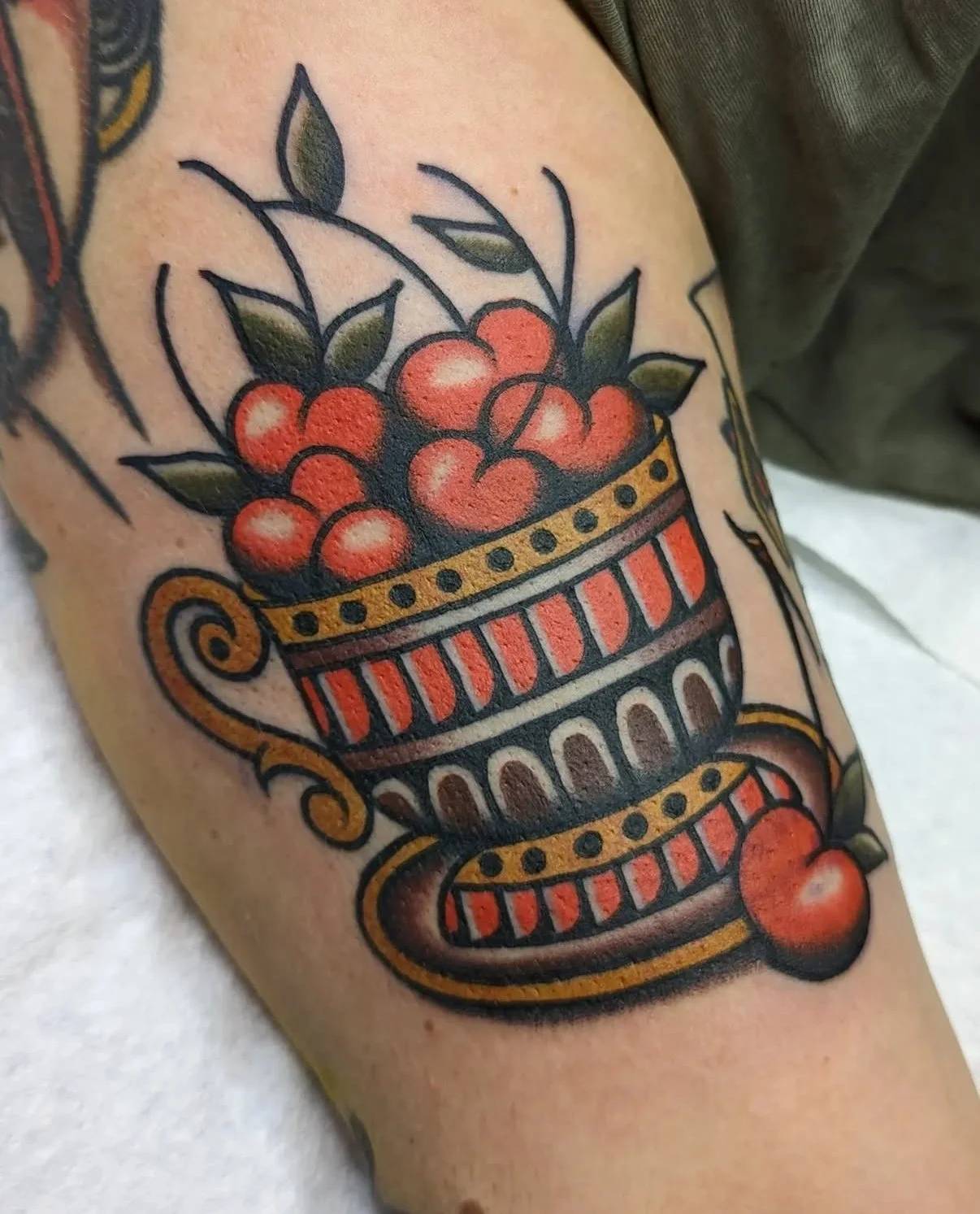 Tatouage d'une corbeille de cerises sur un bras.