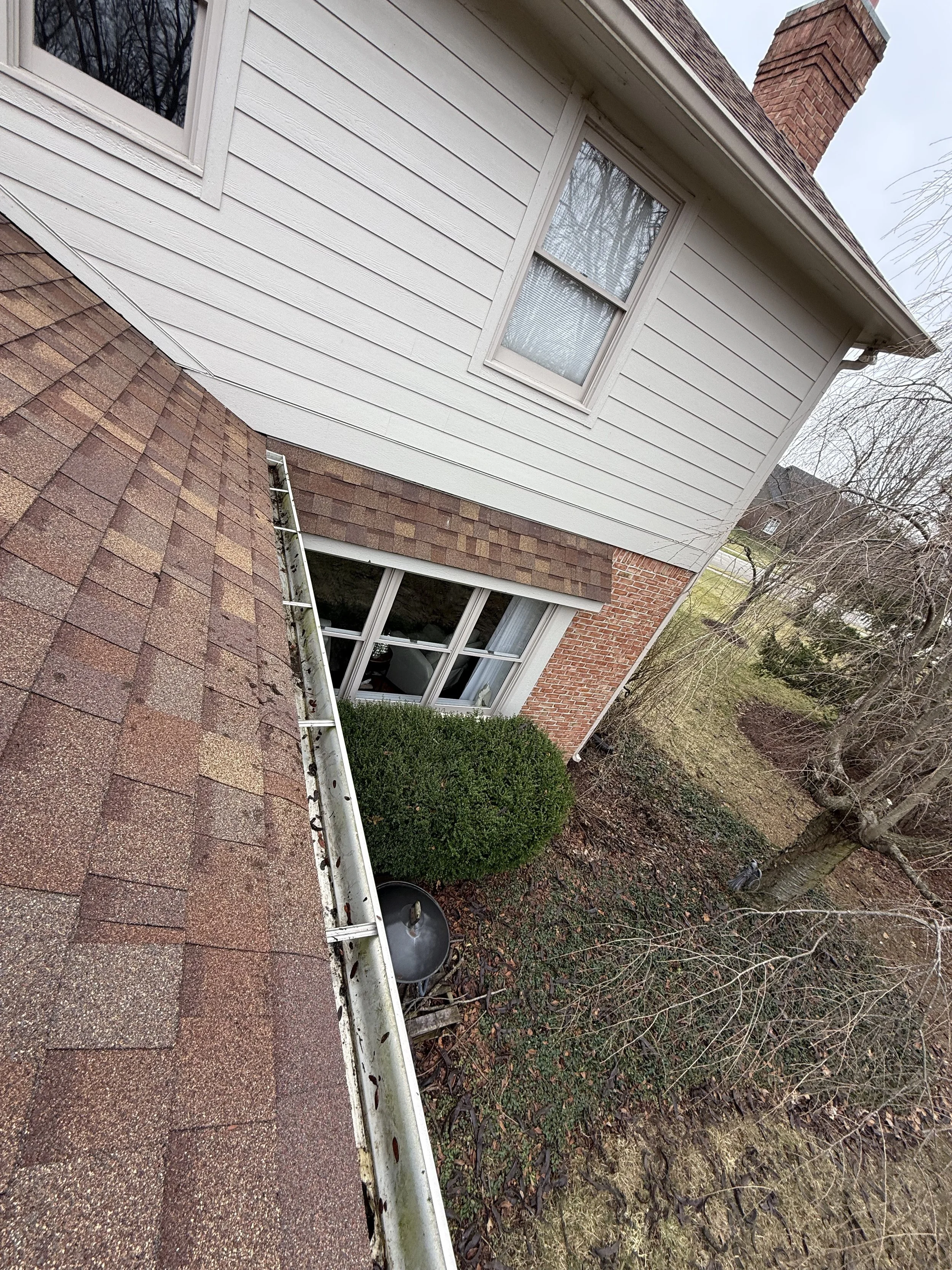 After gutter cleaning on residential home showing clean gutters, roof, and tidy yard
