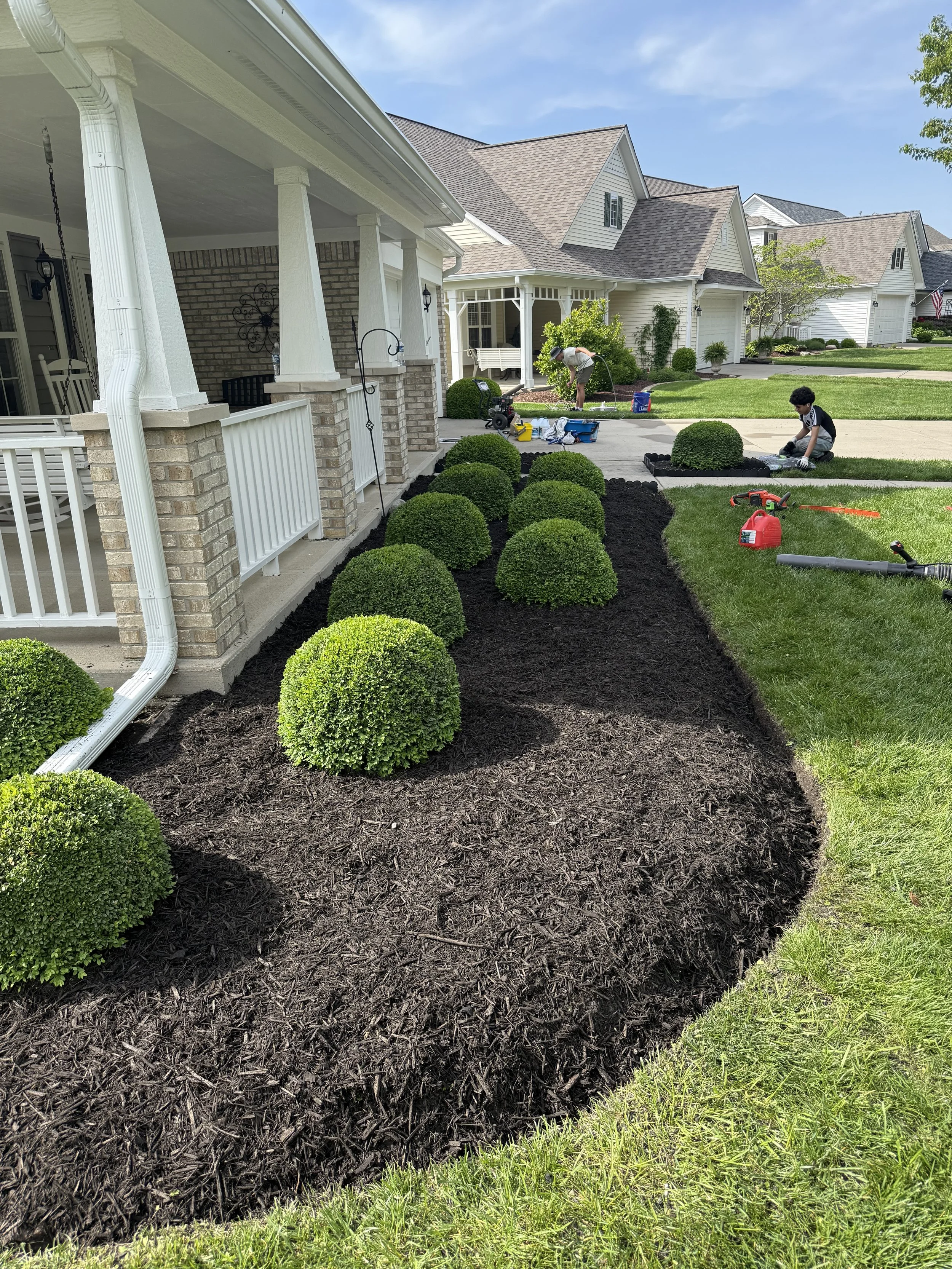 Front yard landscaping with trimmed bushes, clean garden bed edging, and fresh mulch