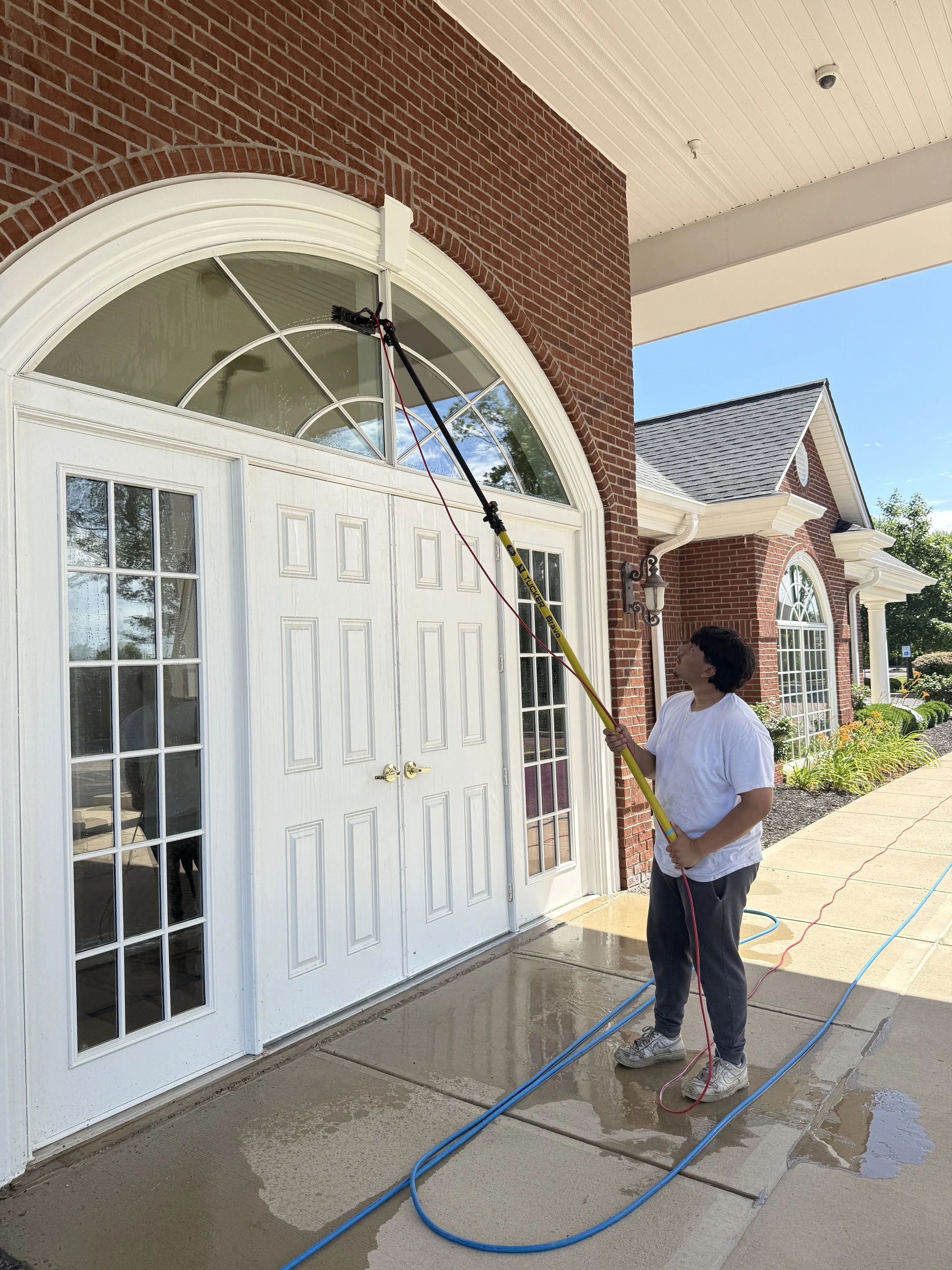 Commercial window cleaning service cleaning exterior entrance windows using water fed pole