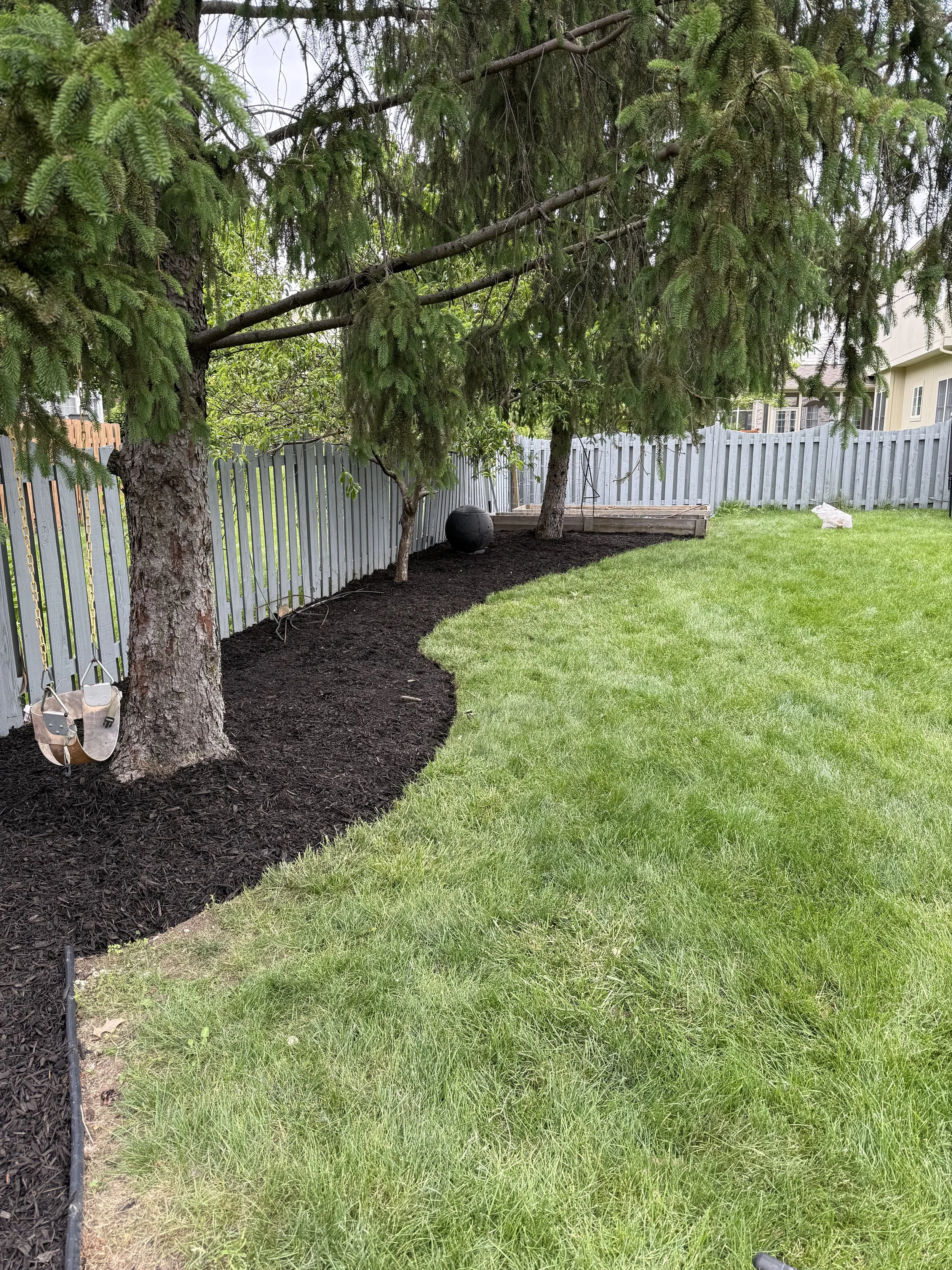 Backyard landscaping with fresh mulch, clean garden bed edging, and cleared debris
