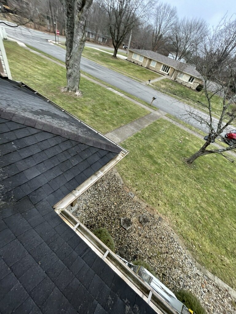 After gutter cleaning on residential home, viewed from roof, with clean gutters, sidewalk, and yard debris removed
