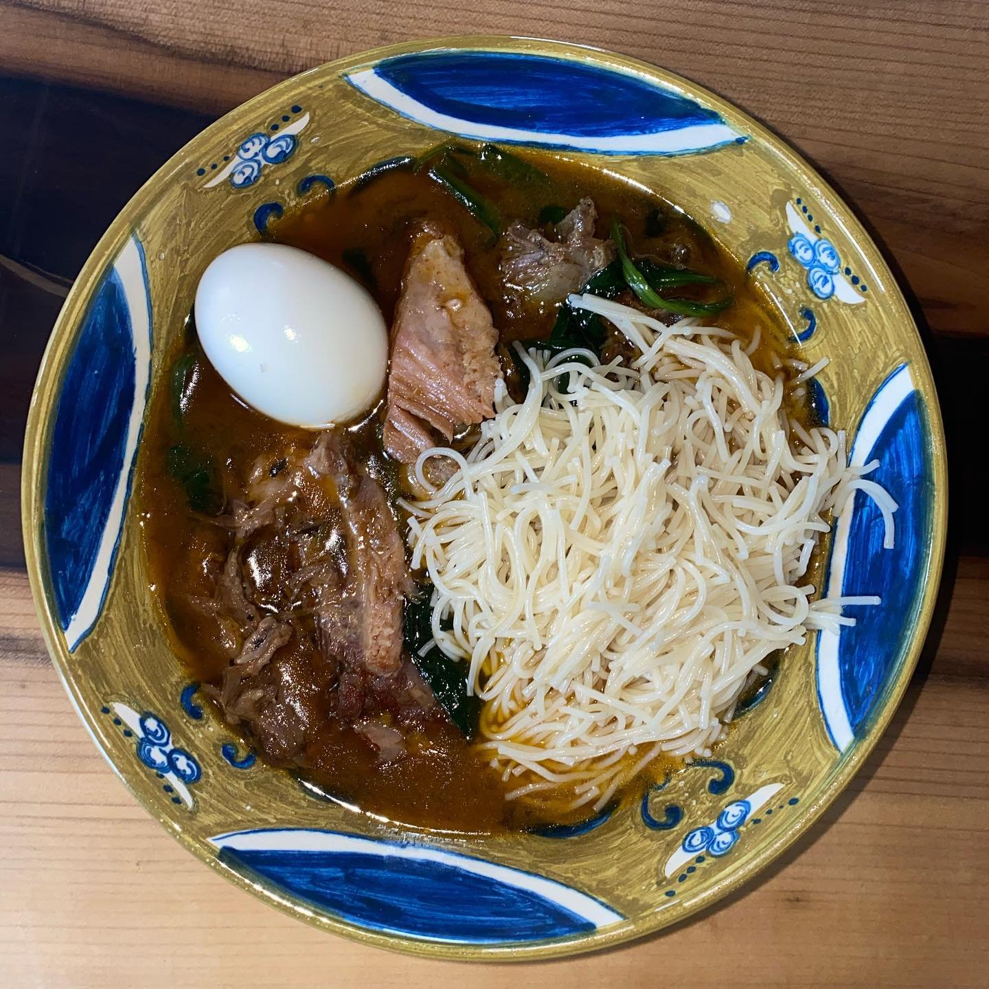 Bowl of ramen with soft-boiled egg, slices of pork, bean sprouts, and green onions in broth