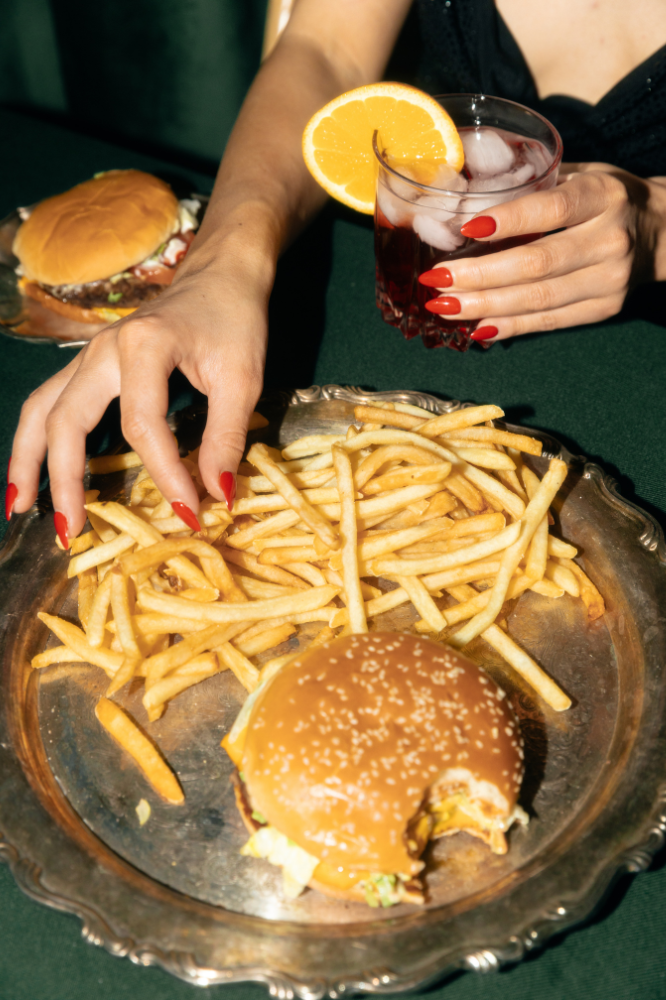 woman at a bar with cocktail and burger