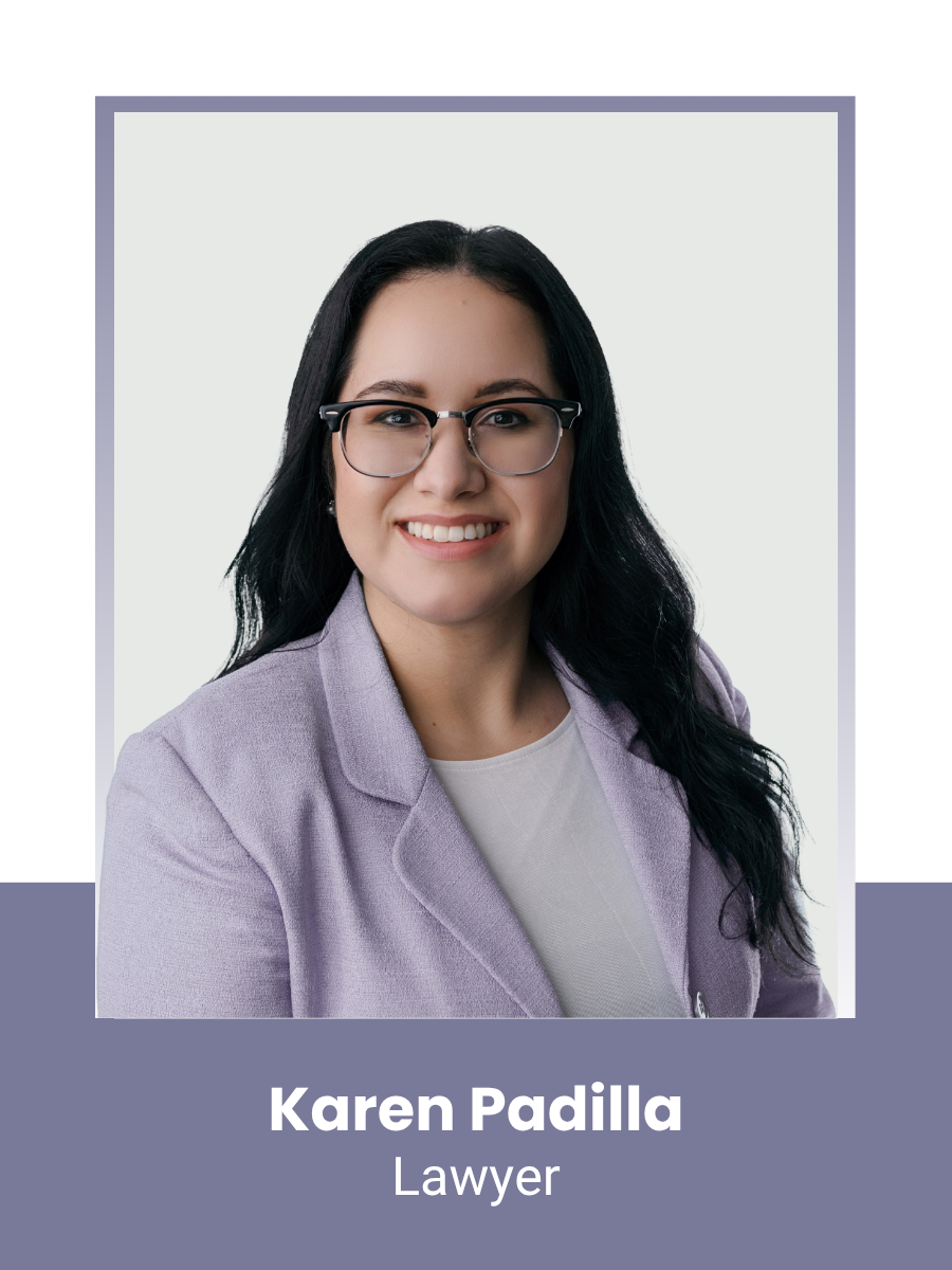 Headshot of a woman with long black hair, glasses, smiling, wearing a lavender blazer and white top, against a light background.