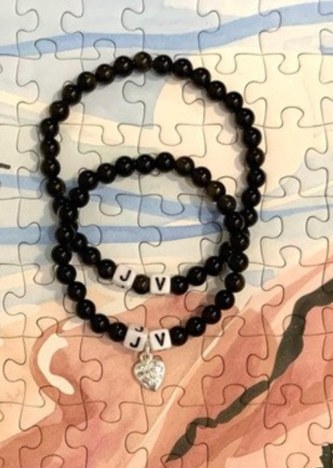 two obsidian custom bracelets with names written and heart charms.