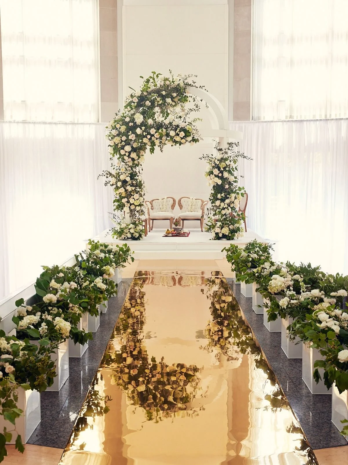The most elegant and fresh floral mandap decor for K and N&rsquo;s gorgeous Hindu wedding.

Lush white blooms popped against the grand structure softened by flowy foliage and accented by a fully lined floral aisle with a gold mirror runner.

Luxury f