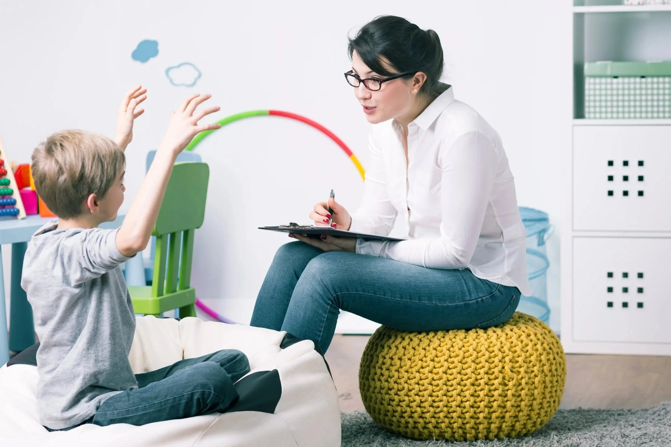 Child and therapist engaging in a therapy session in a playroom.