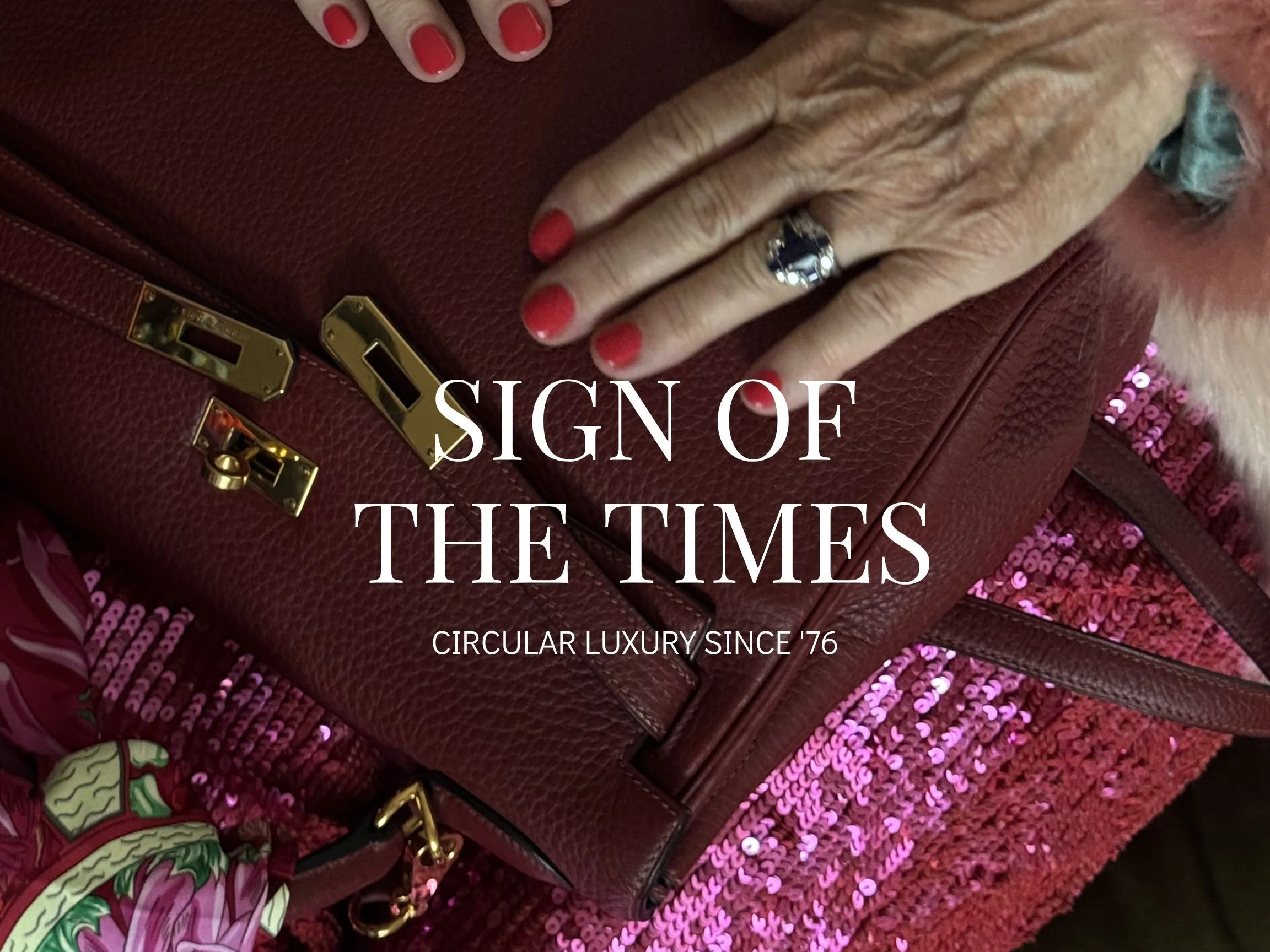 Image of manicured older female hands with red nail polish and ring resting on a burgundy Birkin bag