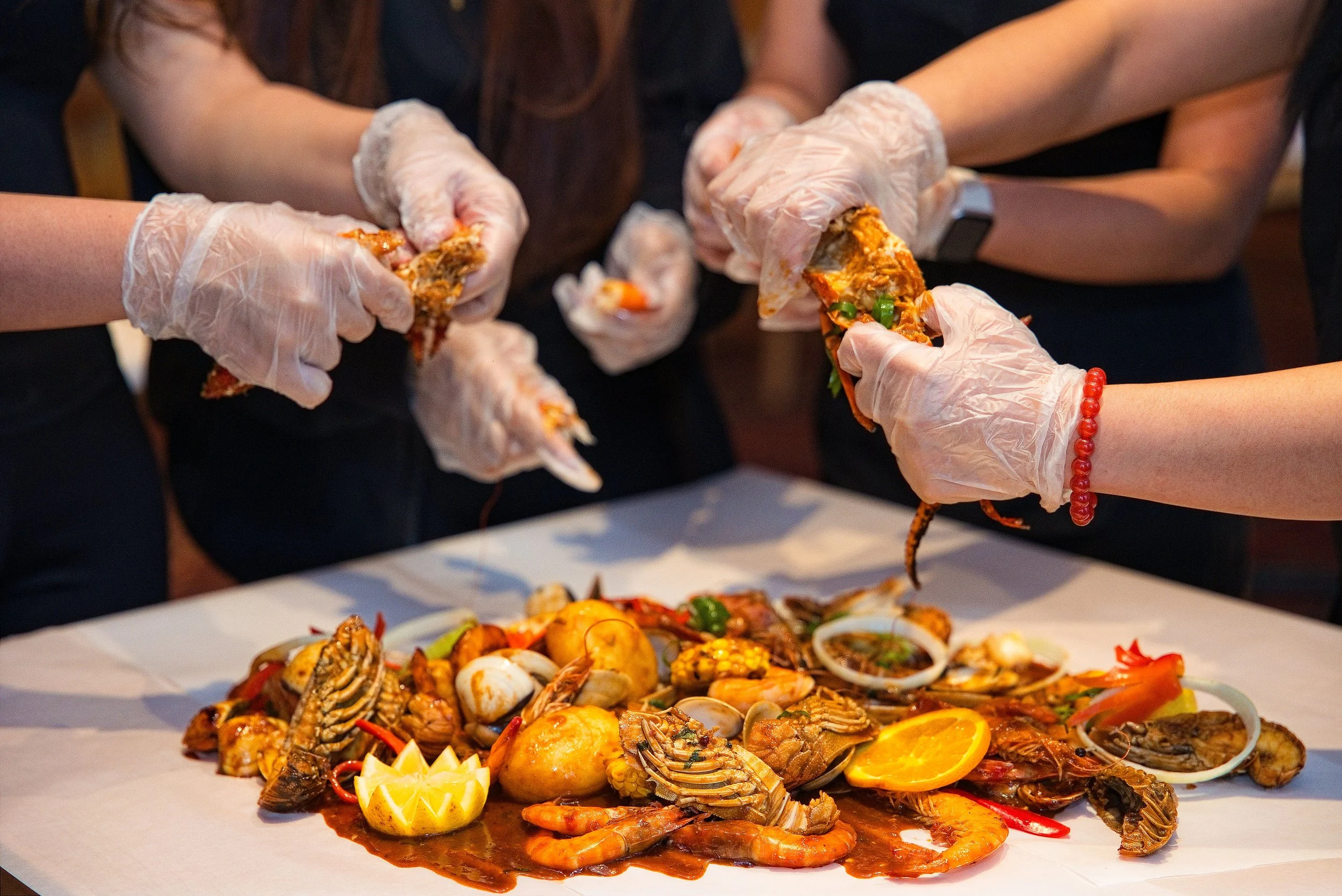 Diners wearing gloves sharing a seafood boil feast at Lusso Tapas Blacktown
