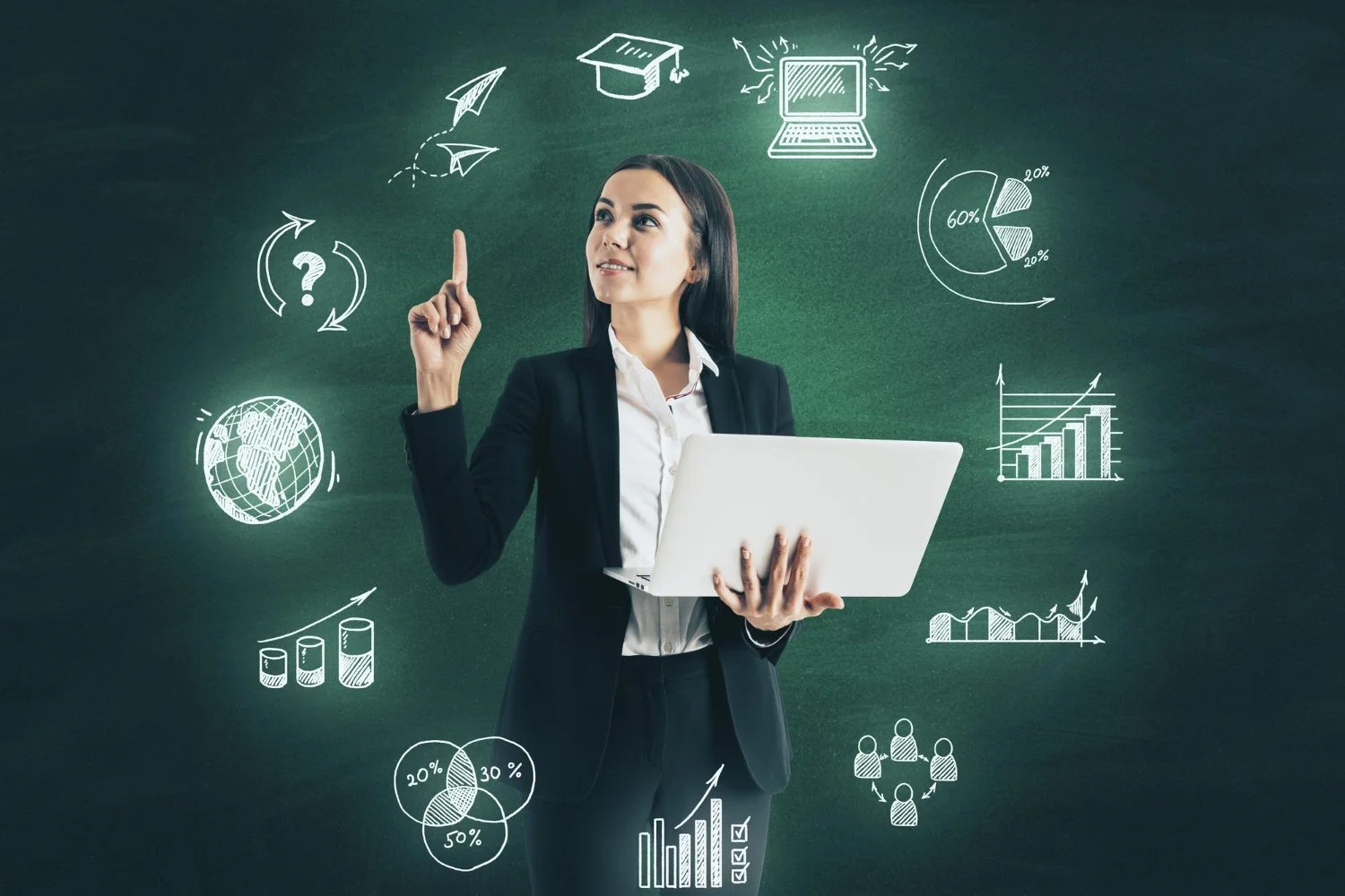 Businesswoman in black blazer holding a laptop with glowing chalk-like business and data icons floating around a green chalkboard background.
