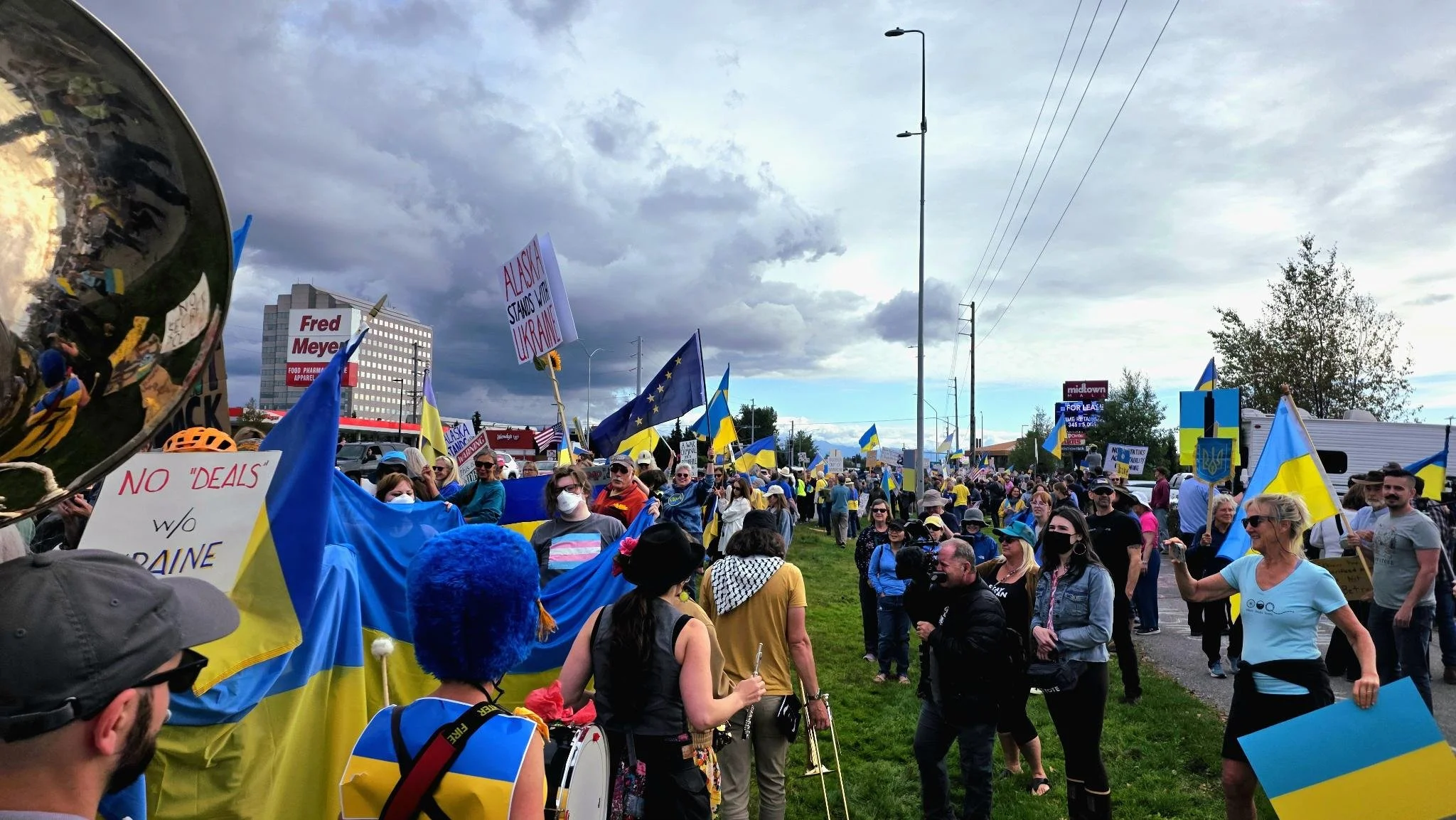 People working on a table creating signs, with one person writing on a large cardboard sign that says 'SAVE THE ENVIRONMENT'.