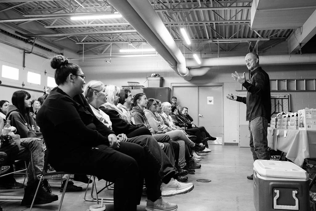 A speaker giving a presentation to a seated audience in an industrial-style room