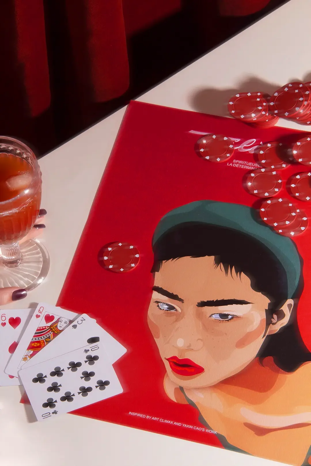 Illustration éditoriale d'une femme asiatique au regard déterminé, décor rouge feutré ambiance poker night, cocktail Bloody Mary, jeu de cartes et jetons, direction artistique et set design rétro.