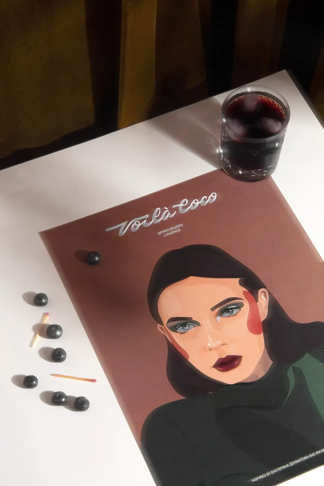 Illustration digitale d'une femme audacieuse plongeant son regard dans le nôtre, décor feutré beige, marron et kaki, myrtilles et allumettes visibles, cocktail kalimotxo foncé, style rétro.