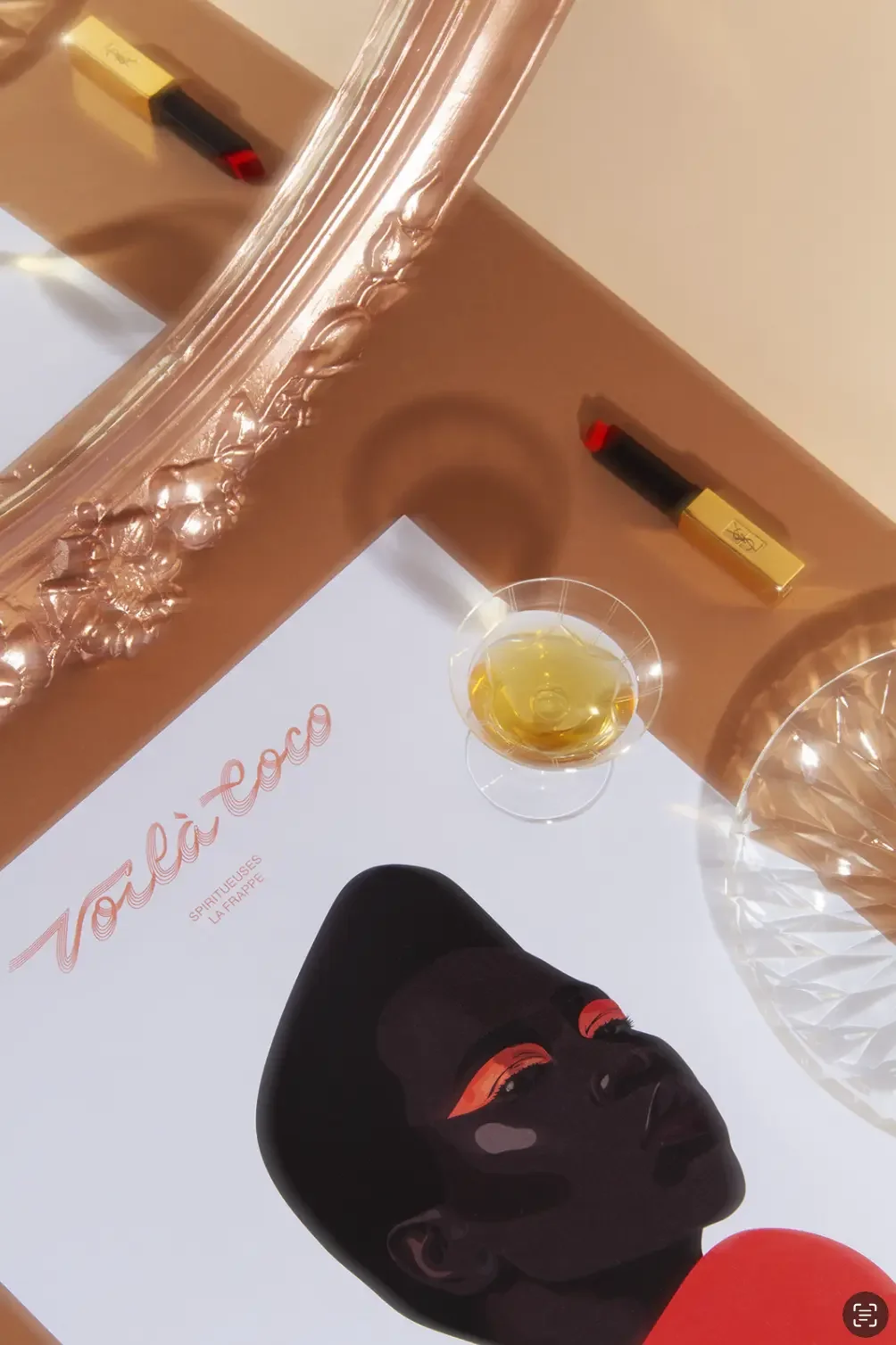Illustration éditoriale d'une femme noire au look année 70 avec regard puissant, décor tons chauds, miroir bronze, cocktail shooter de rhum, rouge à lèvres YSL, assiette en cristal.