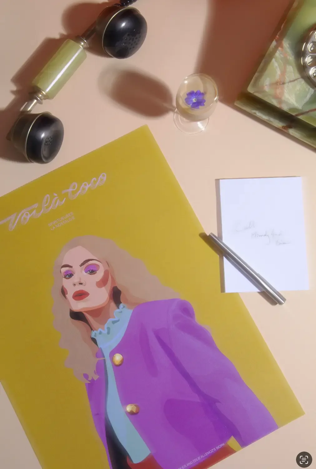 Illustration digitale d'une femme blonde aux cheveux ondulés avec maquillage et tenue rétro violette, décor rétro feutré avec téléphone marbre, cocktail Baileys et fleur violette, carnet de note.