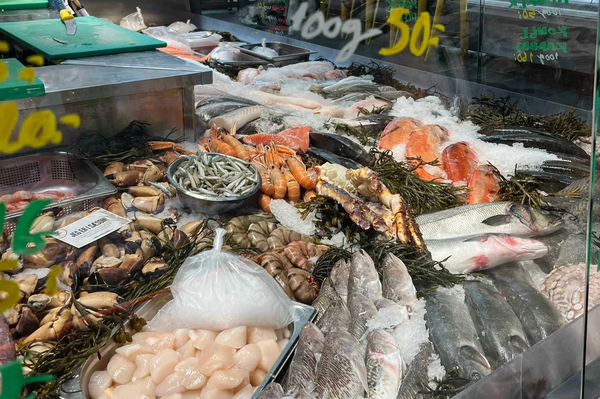 Display of fresh seafood including fish, shrimp, and other shellfish on ice at a fish market.