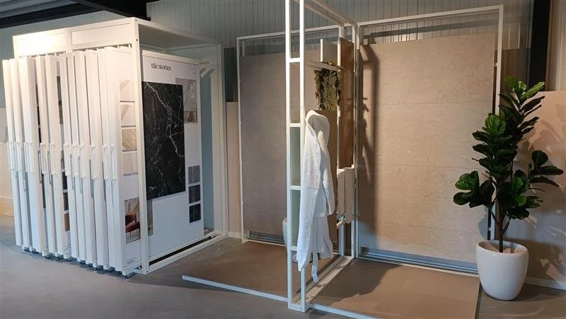 Een opslagruimte met verschillende wand- en vloerpanelen en een grote groene plant in een witte pot.