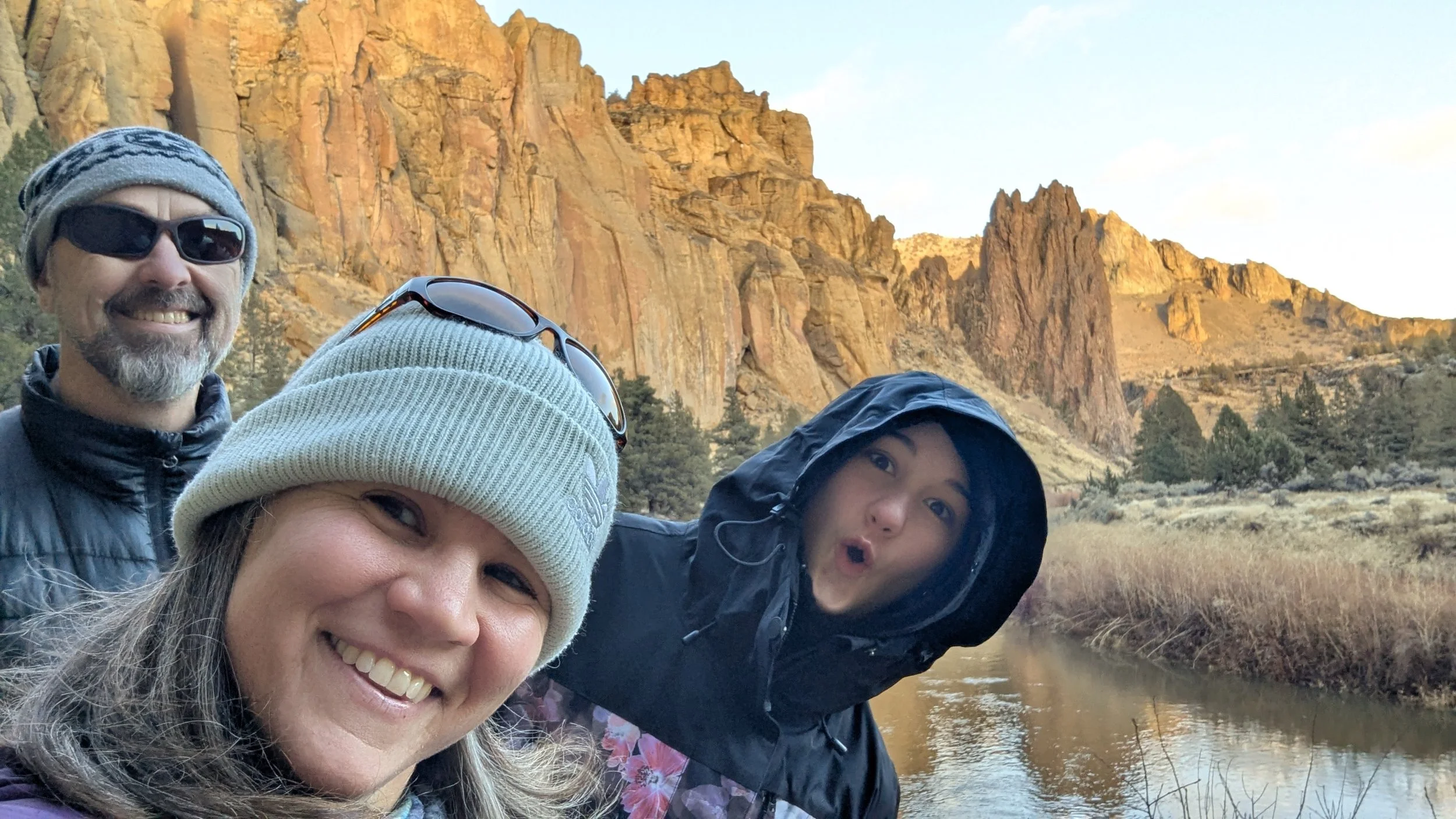 3 people looking at the camera with brown rocks in backdrop