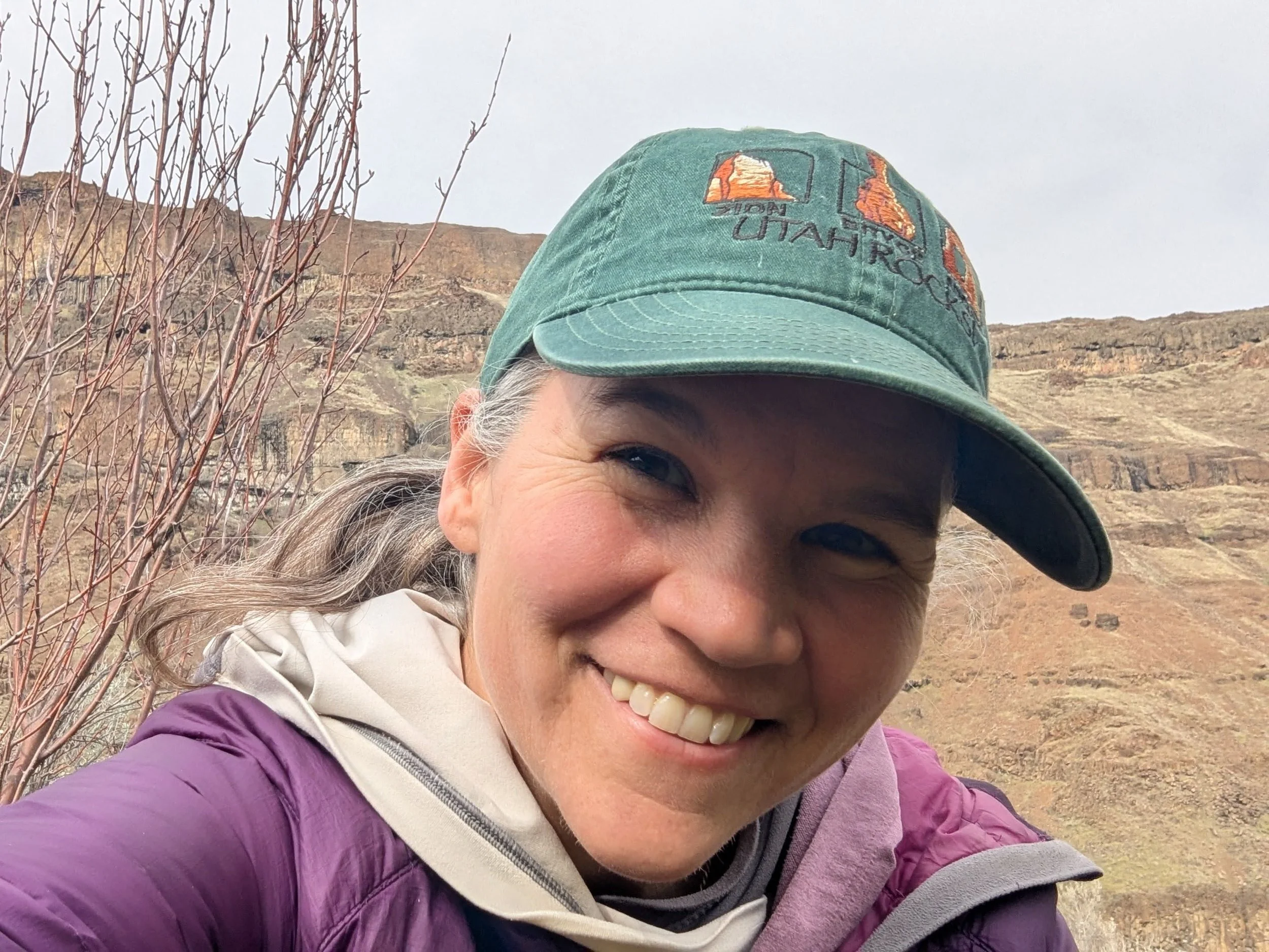 woman in a green hat smiling in a rock canyon