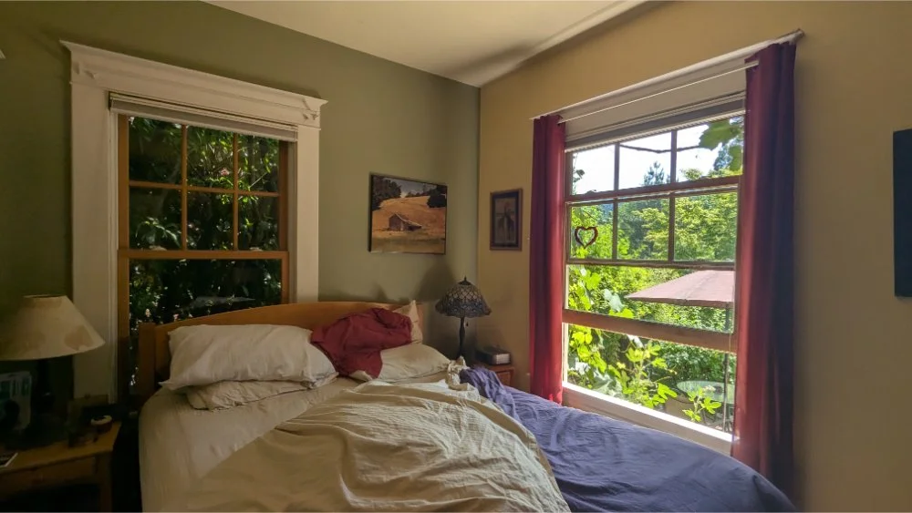 an unmade bed with a blue comforter, brown sheet and green and yellow walls