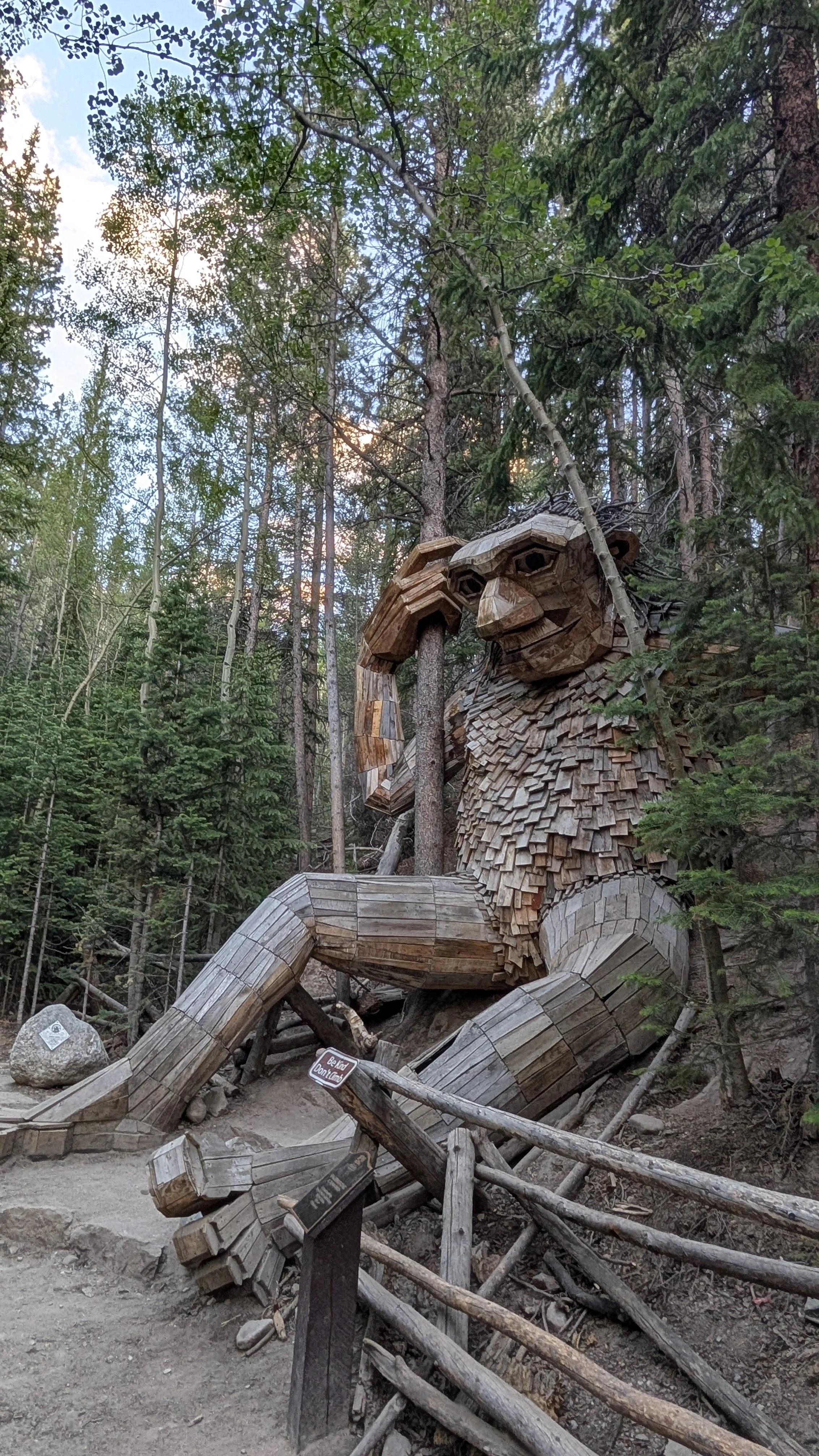 large wooden statue of a troll in a green forest