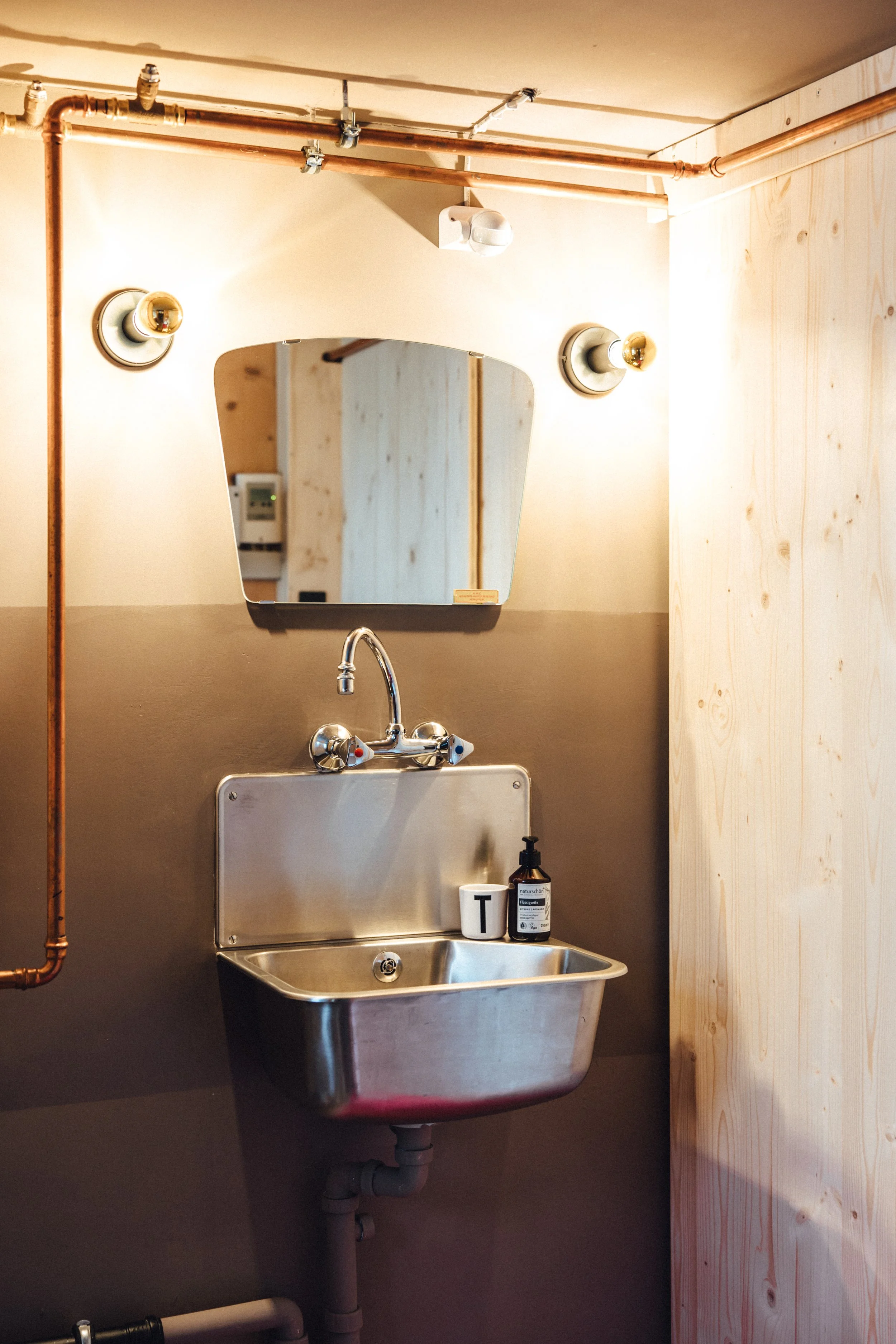 industrial design Bad mit Kupferrohren und Retro Waschbecken, Vintage Spiegel und Gold Glühbirnen