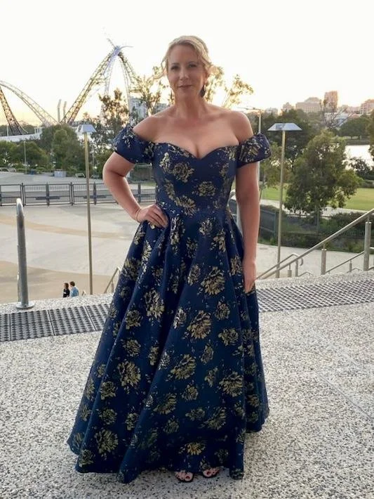 Modern wooden cabin with large window amid grassy landscape, against a backdrop of mountains.