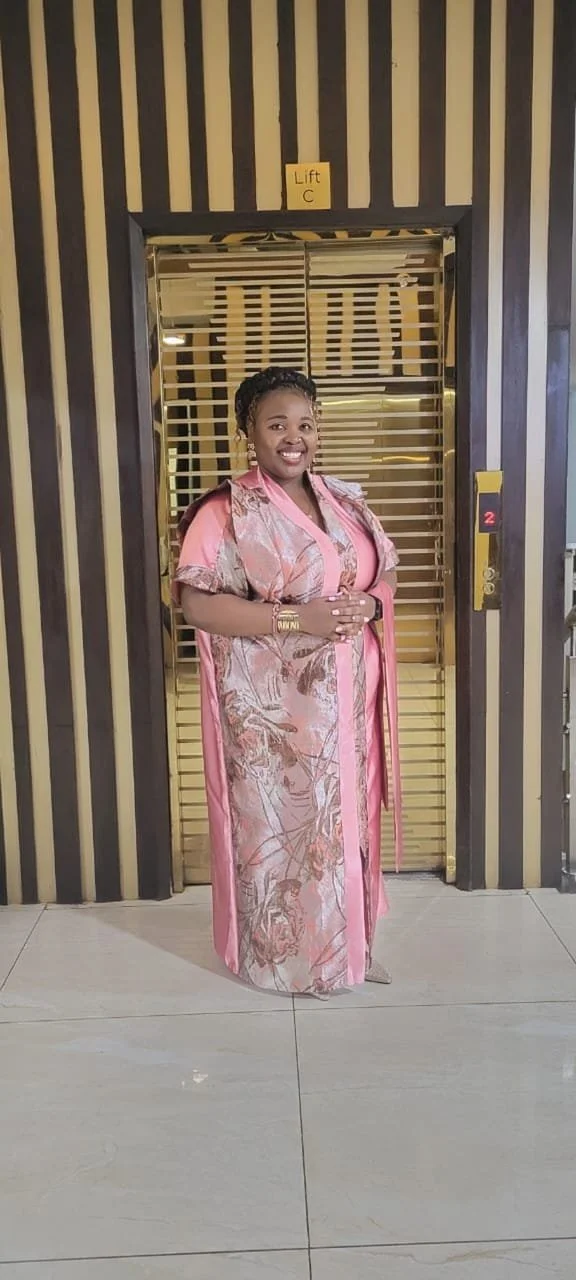 Modern house on grassy hill with snow-capped mountains in the background under a cloudy sky.