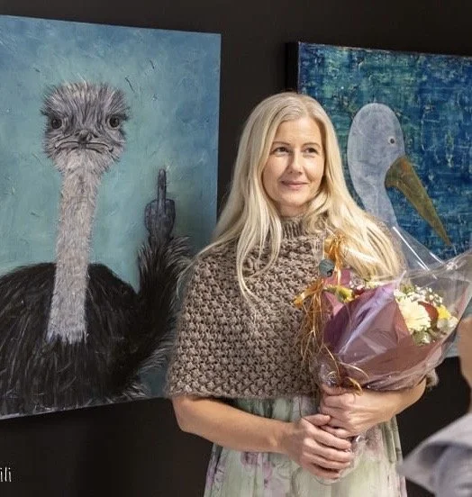 Kvinne med blomster foran kunstmaleri av struts og fugl.