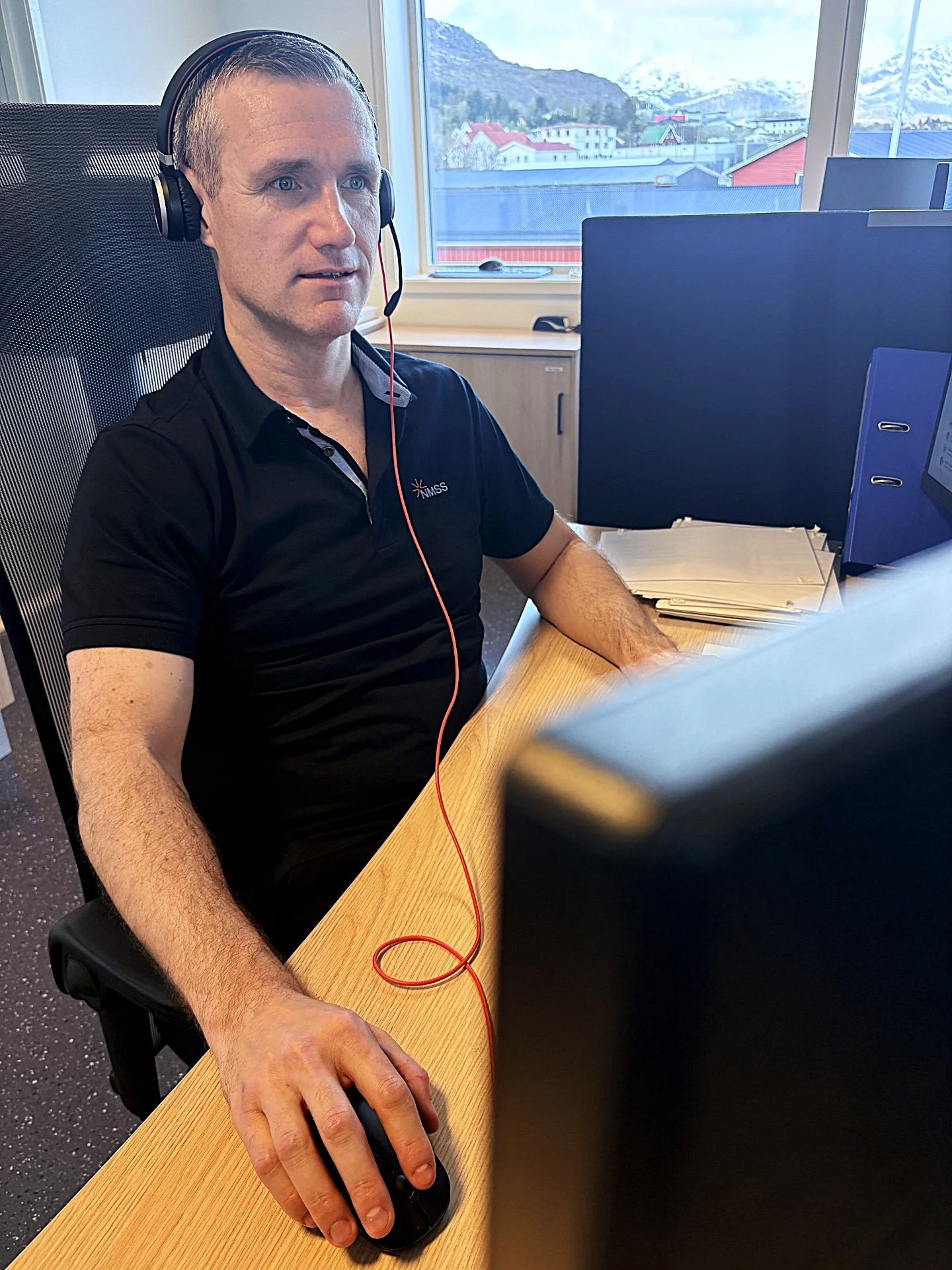 Carl-Erik sitter ved pc og har telefonen koblet til headset.