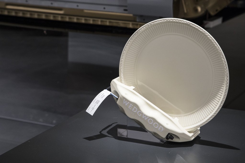 White ceramic plate with "Wedgwood" written on a stand, displayed in a museum setting.