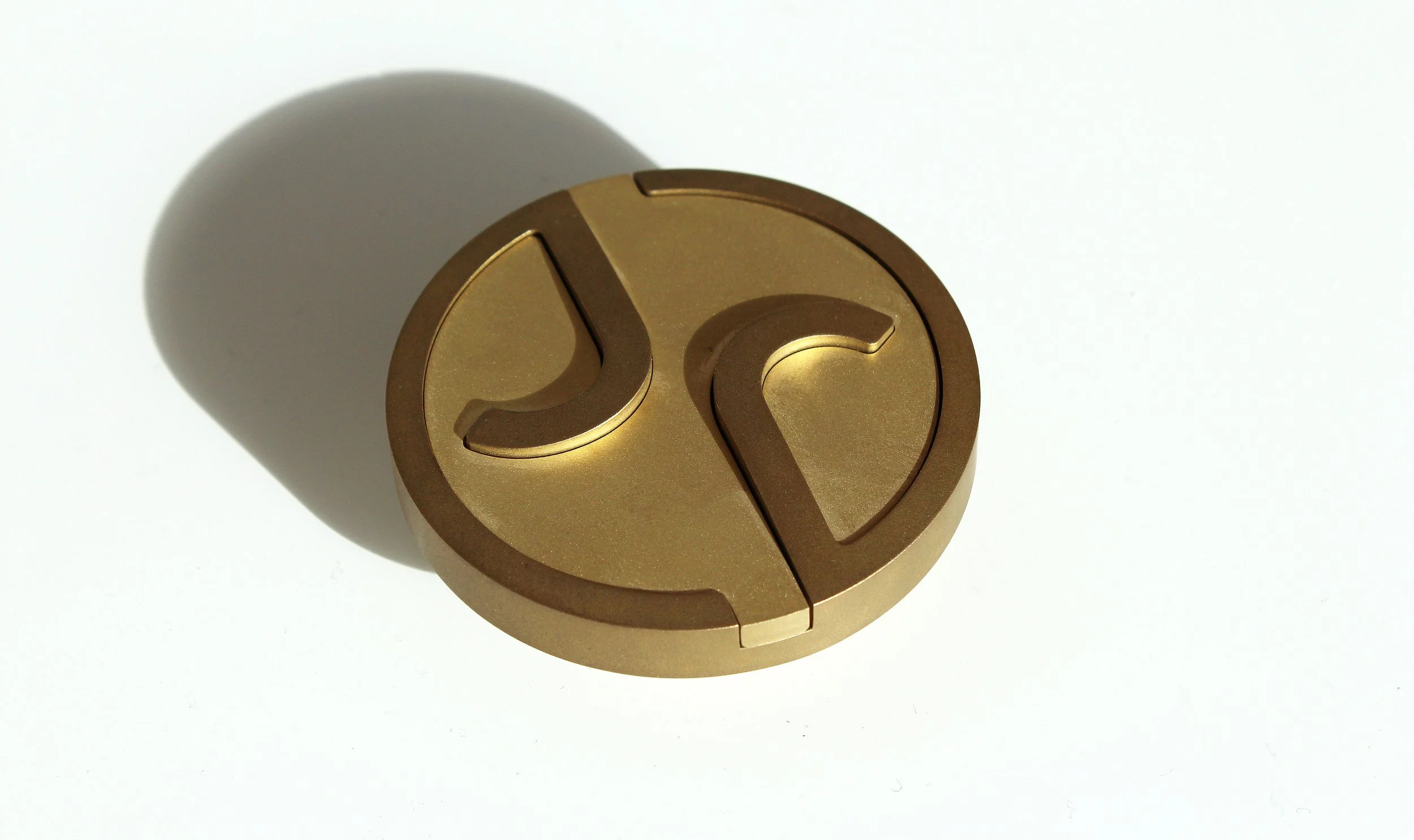Round golden metal object with cut-out designs on a white background.