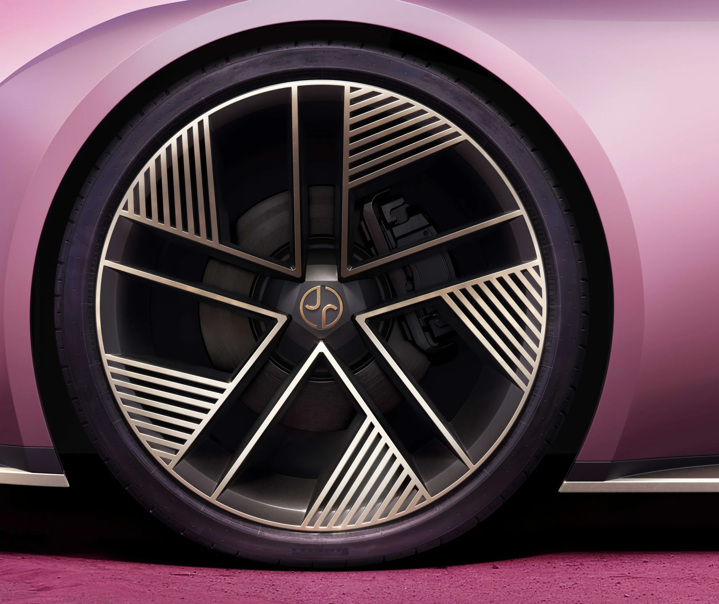 Close-up of a car wheel with a detailed, artistic rim design in silver and black.