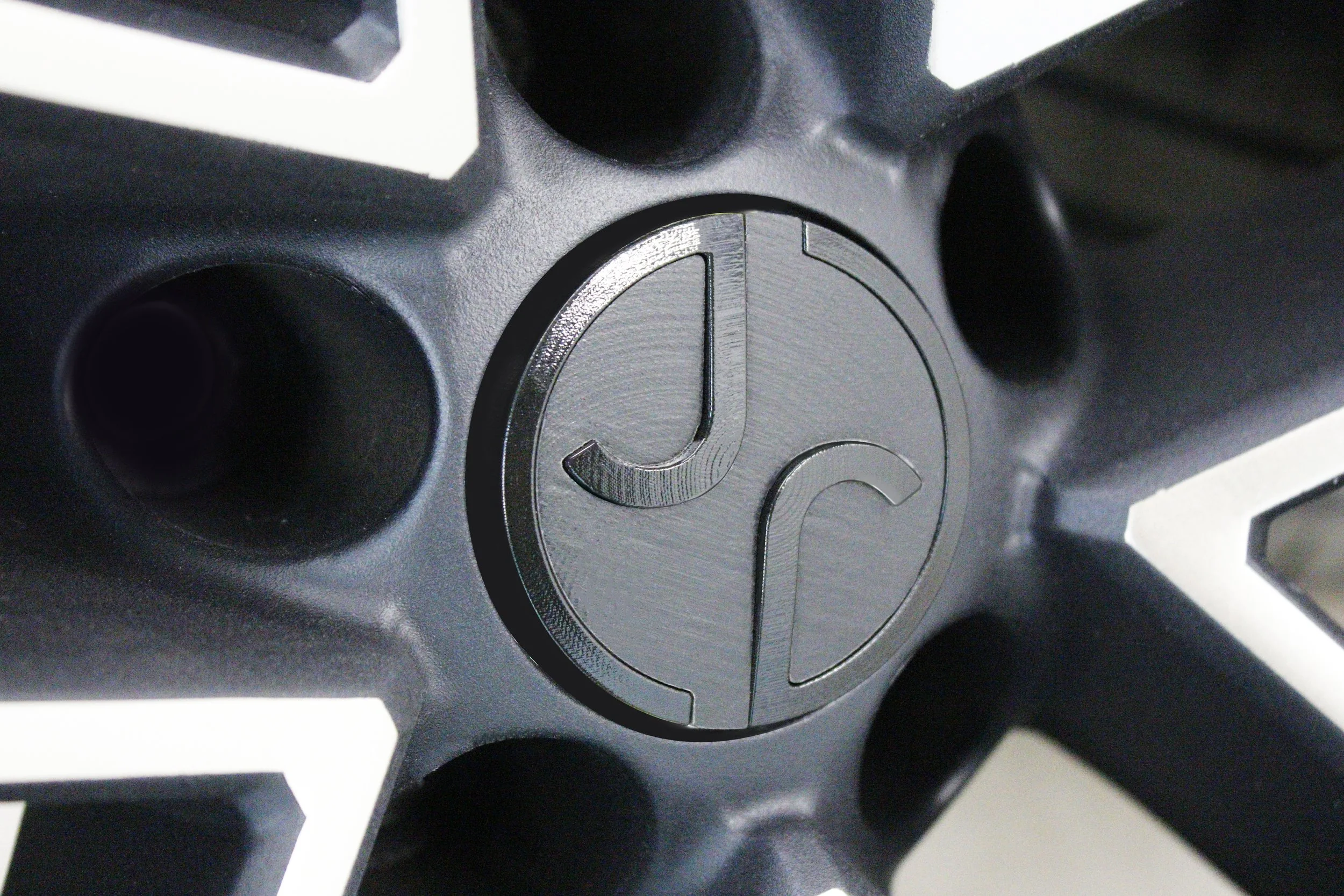 Close-up of a black custom alloy wheel center cap with engraved logo design.