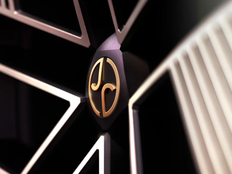 Close-up of a gold logo on a black background with geometric patterns.