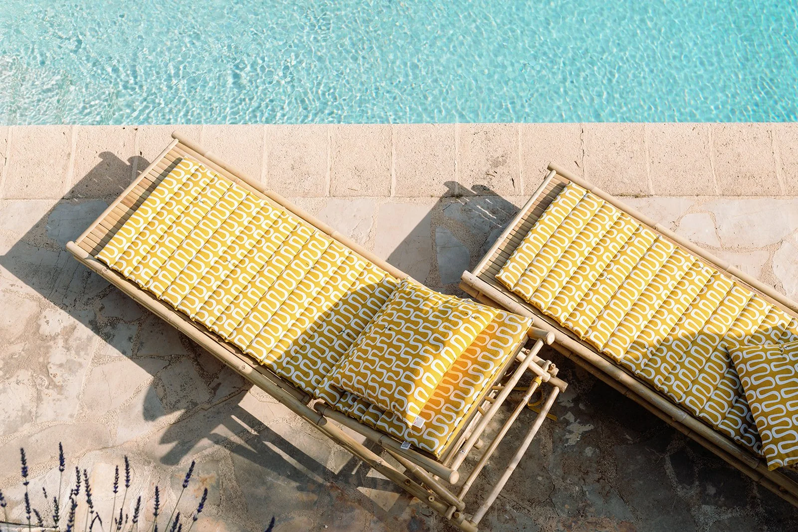 Yellow patterned lounge chairs beside a turquoise swimming pool
