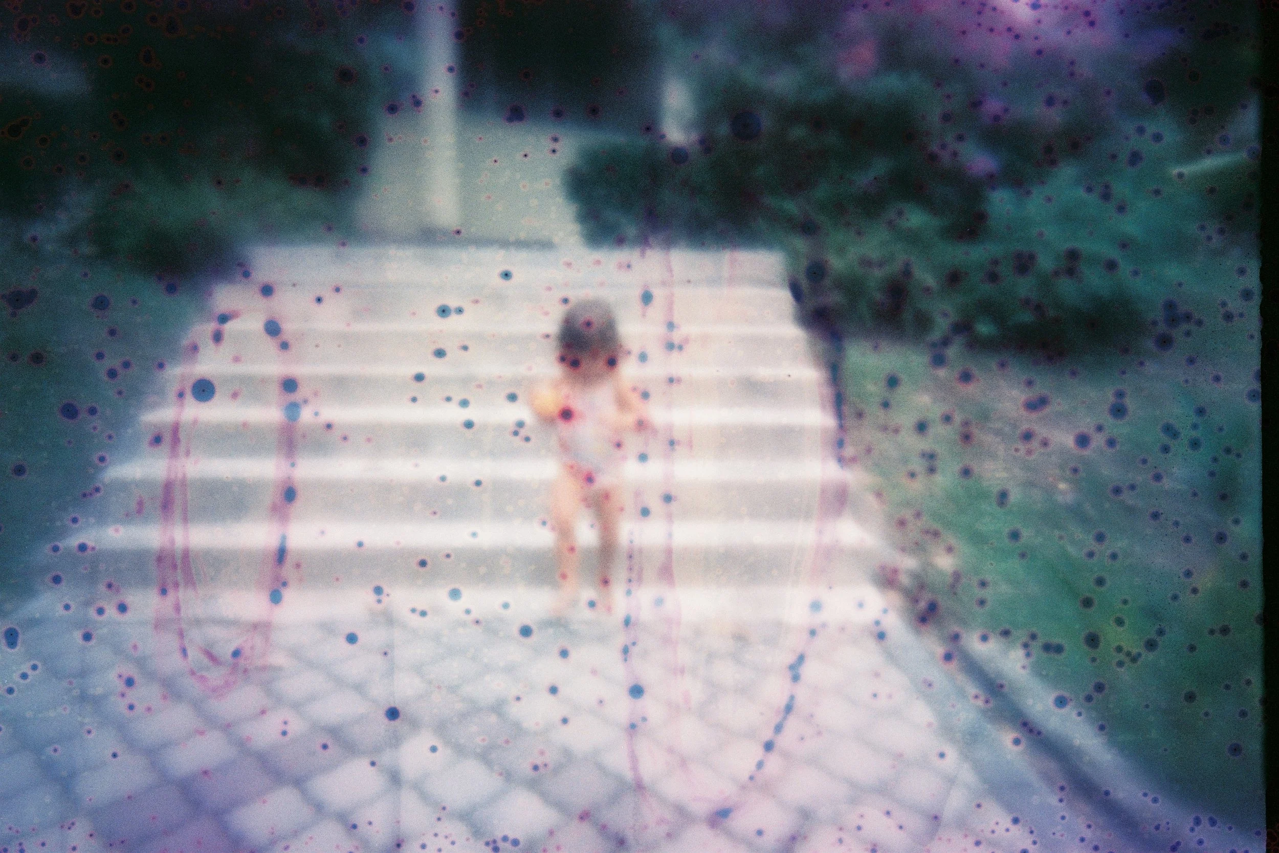 une image argentique de film soup avec une enfant qui descend les escaliers en pierre dans un jardin