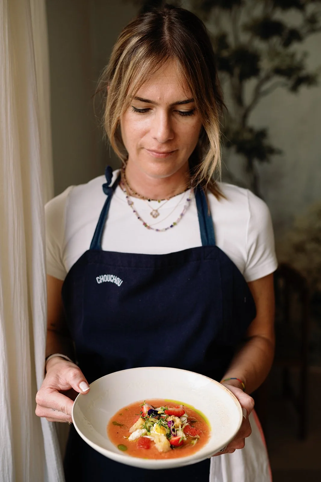 femme blonde cheffe cuisinier tient dans ses mains un plat coloré